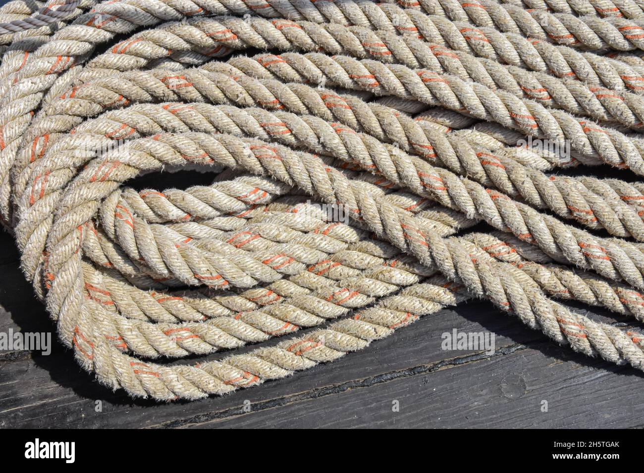 Rope folded in a neat and orderly pattern on the deck of a sailing vessel. Stock Photo
