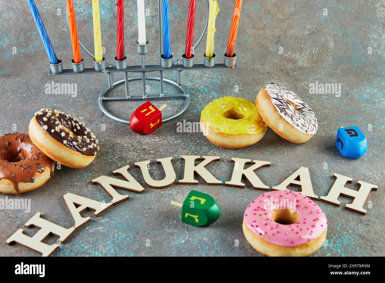 Happy Hanukkah and Hanukkah Sameach - traditional Jewish candlestick with candles, donuts and spinning tops with the inscription Hanukkah. Stock Photo