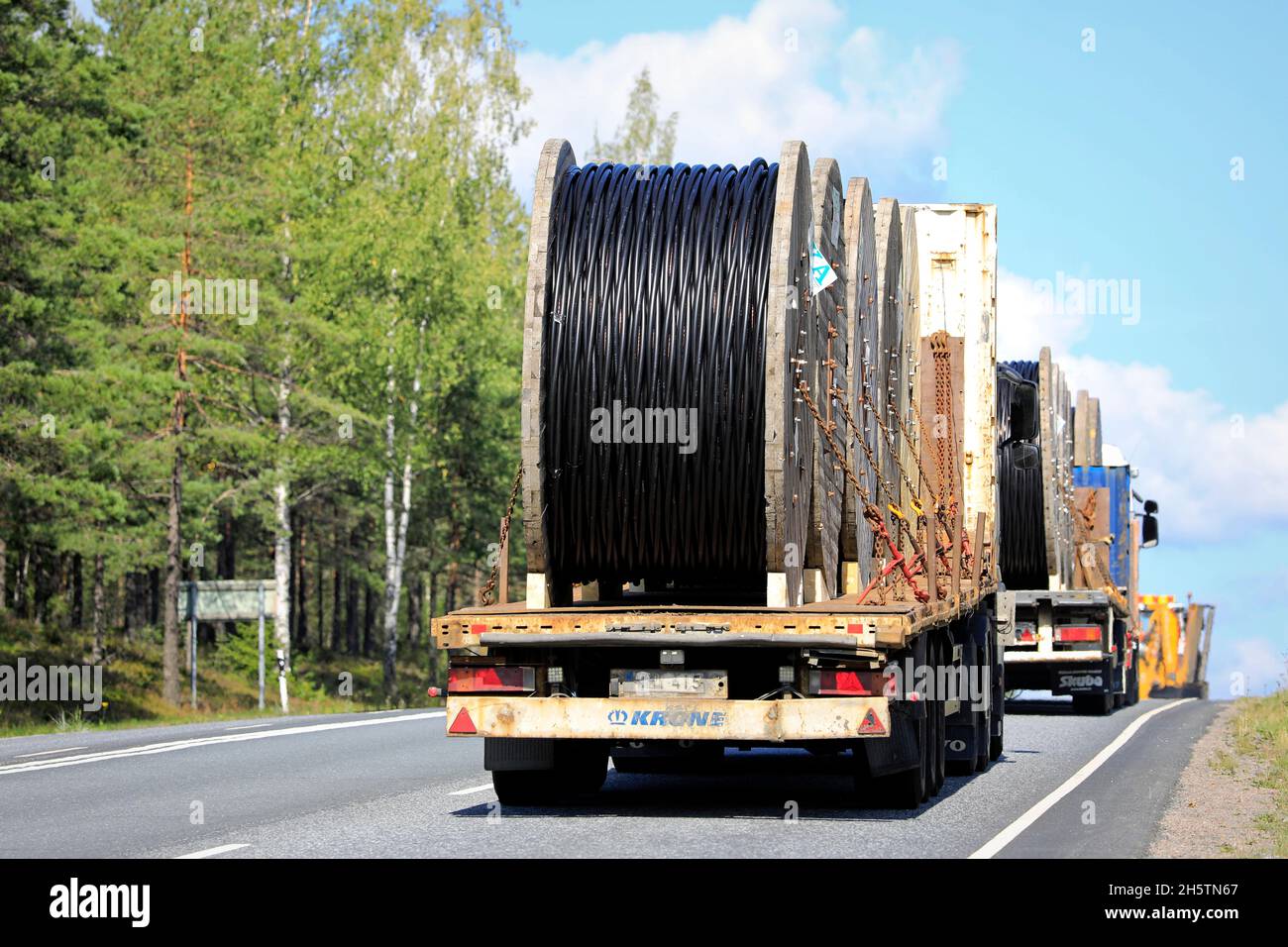 Flatbed trucks transport REKA power cable drums, secured with chains. Rear view. Highway 3, Ikaalinen, Finland. August 12, 2021. Stock Photo