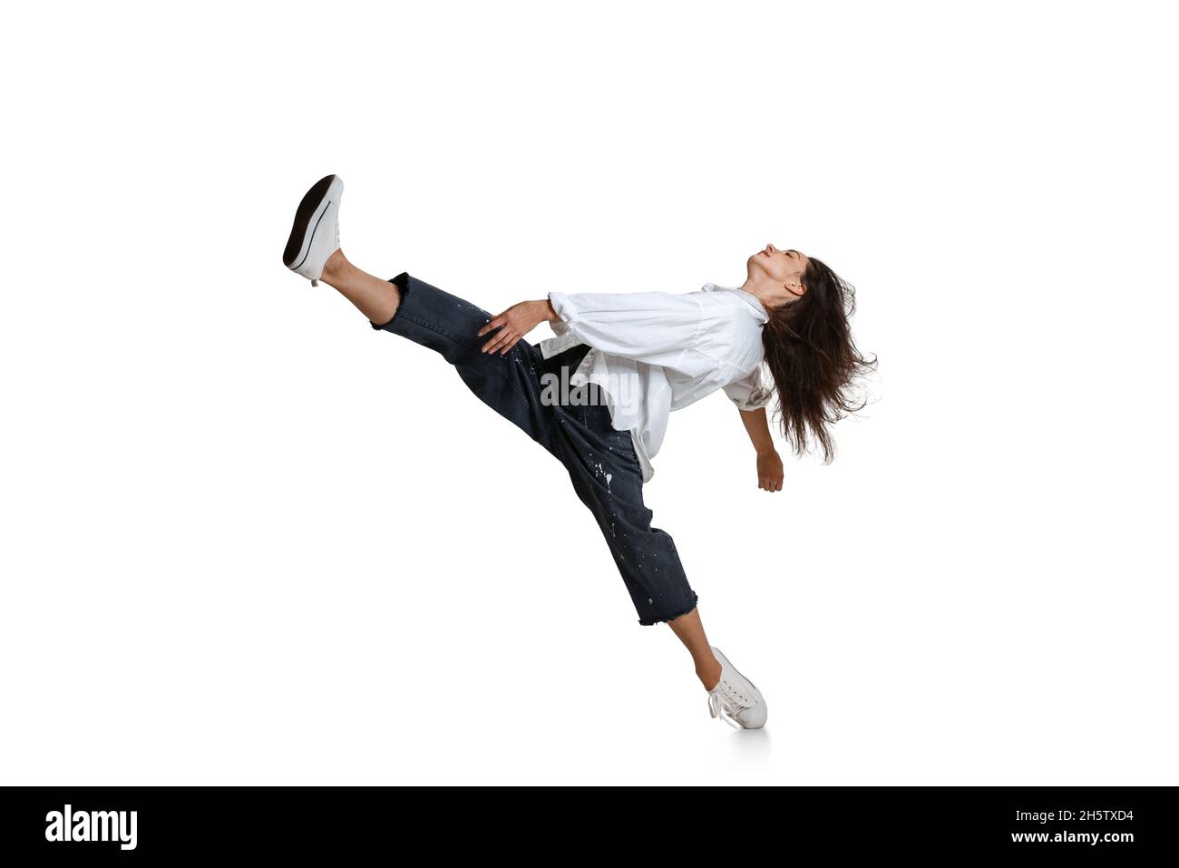 Young woman in casual wear moves dynamically isolated on white background. Art, motion, action, flexibility, inspiration concept. Stock Photo