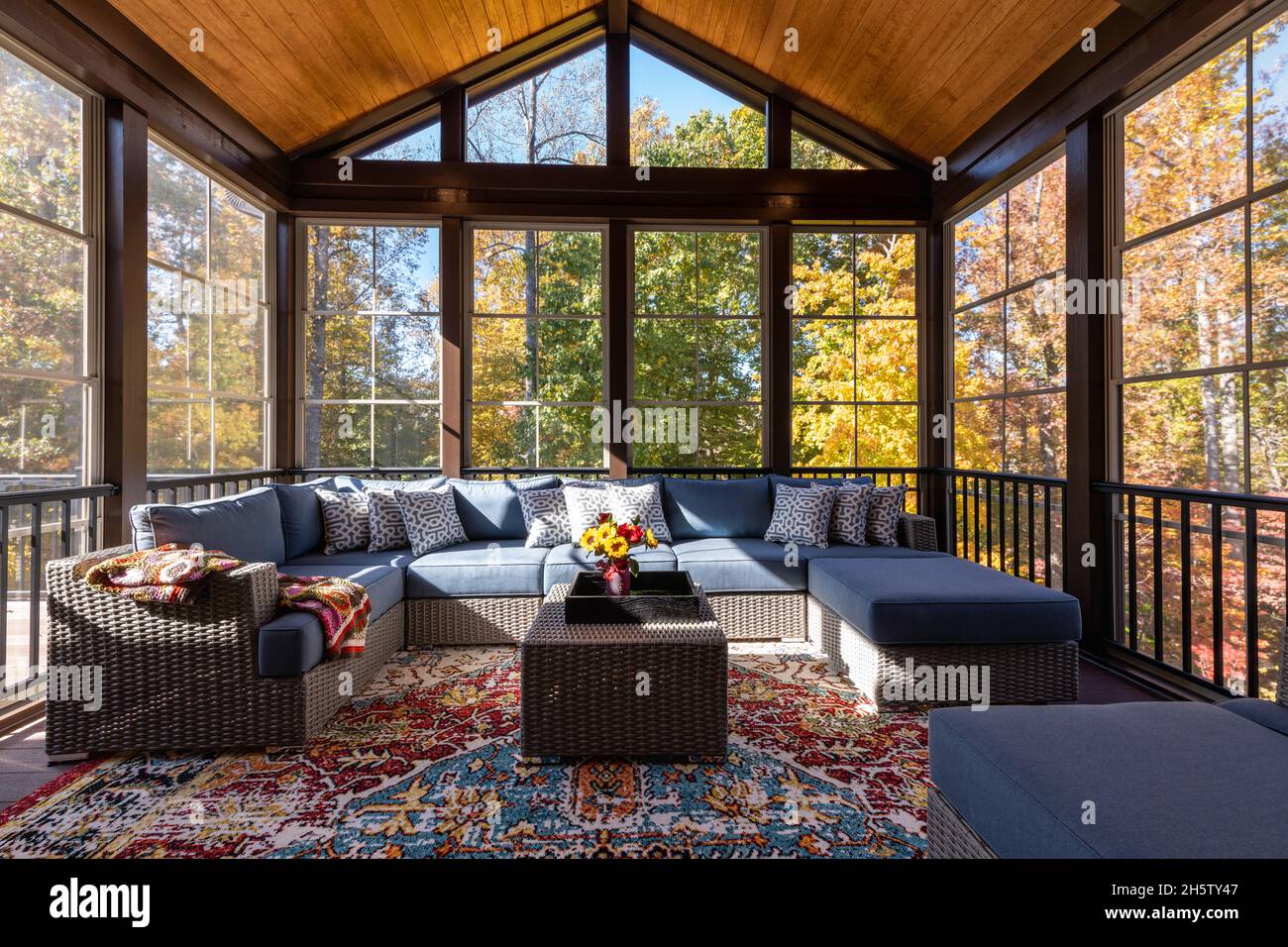 New modern screened porch with patio furniture, summertime woods in the background. Stock Photo