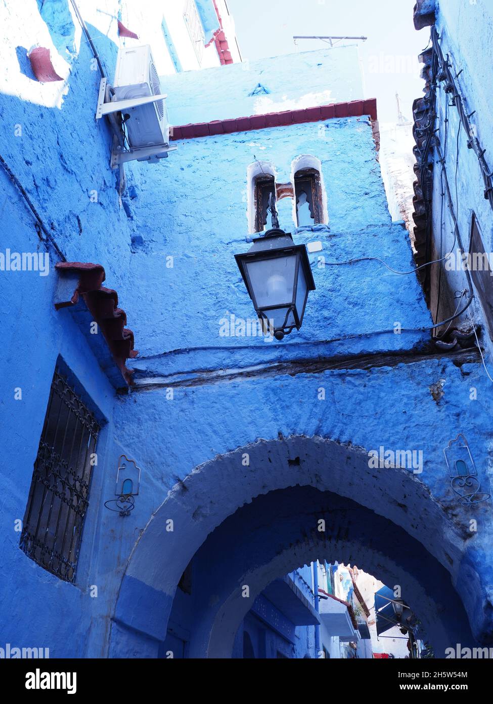 Gate in moroccan alley in african Chefchaouen city in Morocco, clear blue sky in 2019 warm sunny spring day on April - vertical Stock Photo