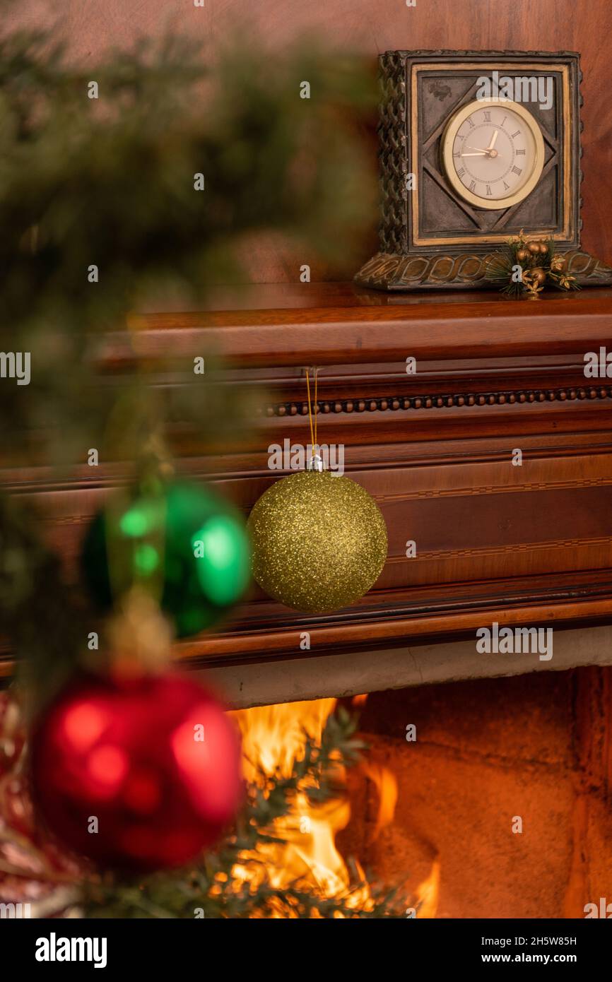 https://c8.alamy.com/comp/2H5W85H/december-with-christmas-decoration-with-a-wooden-fireplace-with-an-old-clock-with-a-tree-branch-with-hanging-colorful-spheres-decoration-and-home-2H5W85H.jpg