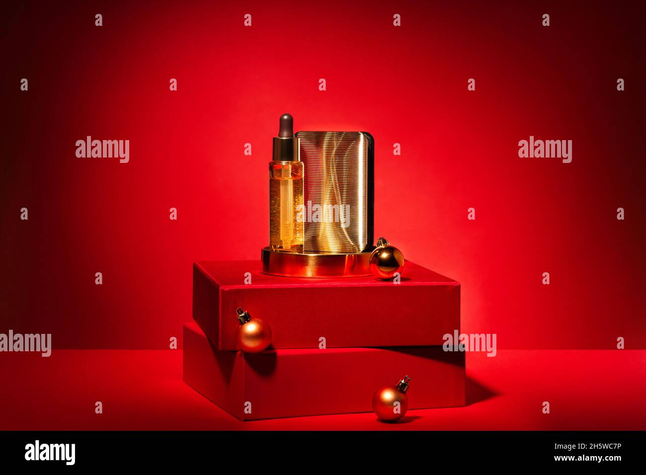 Gold cosmetics on a red podium with gift boxes and decor on a red background. Pedestal, showcase with luxury cosmetics. Holiday advertising concept fo Stock Photo