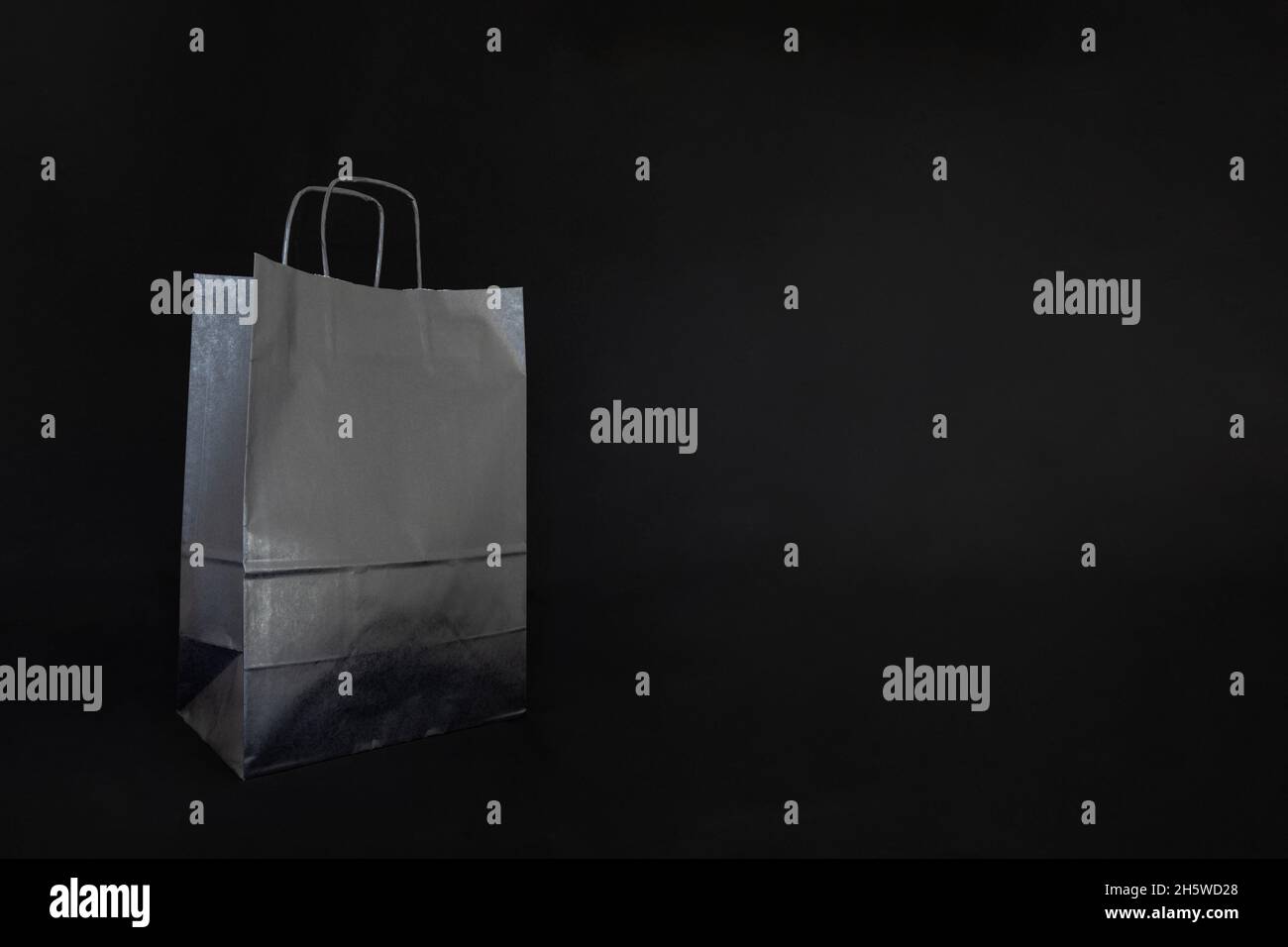 Black paper shopping bag isolated on dark background with space for
