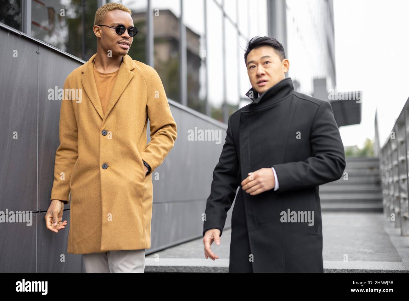 Businessmen walking on city street and talking Stock Photo - Alamy