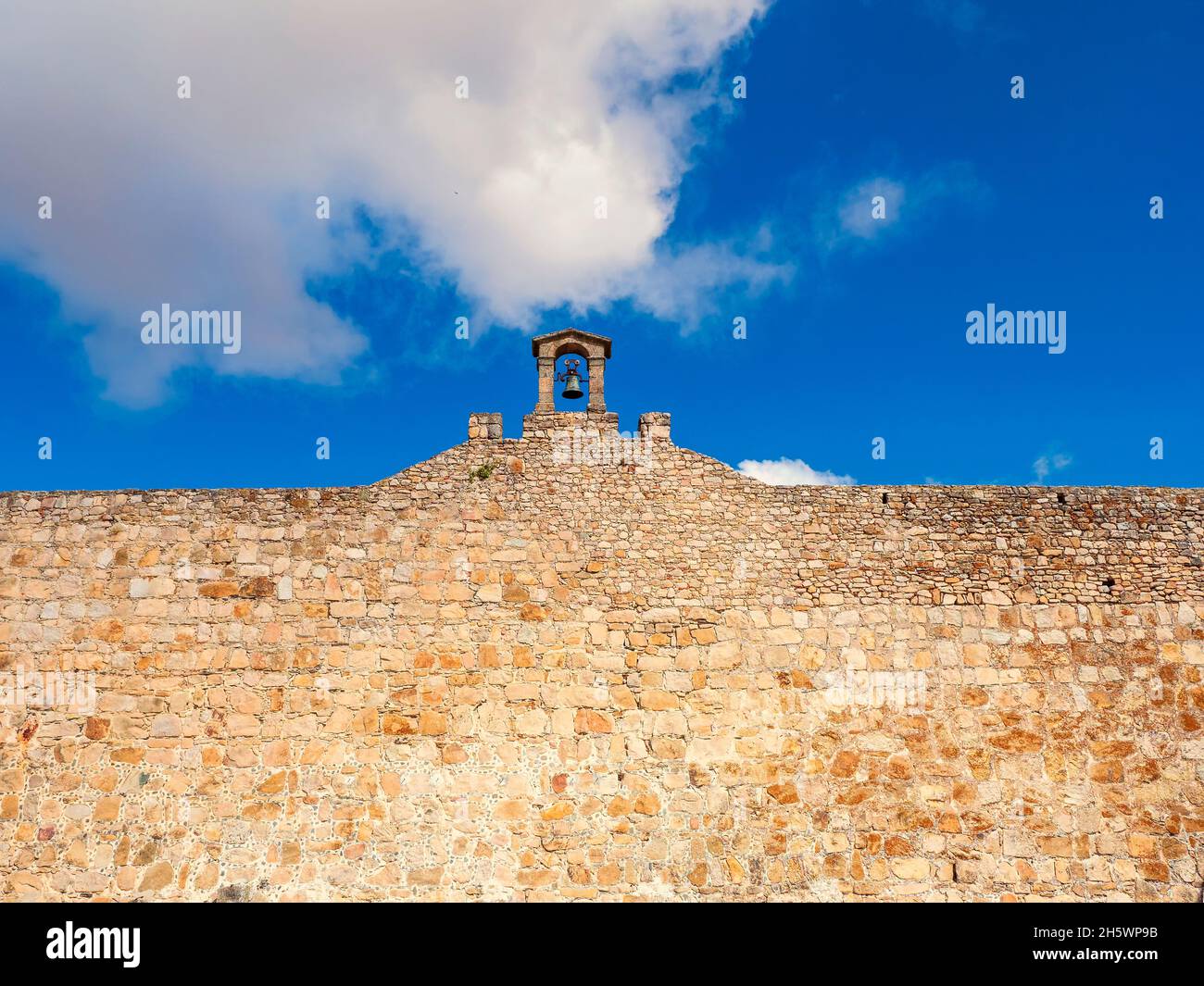 Stone arch with a large bell on the wall of the castle of Trujillo de Cáceres. Stock Photo
