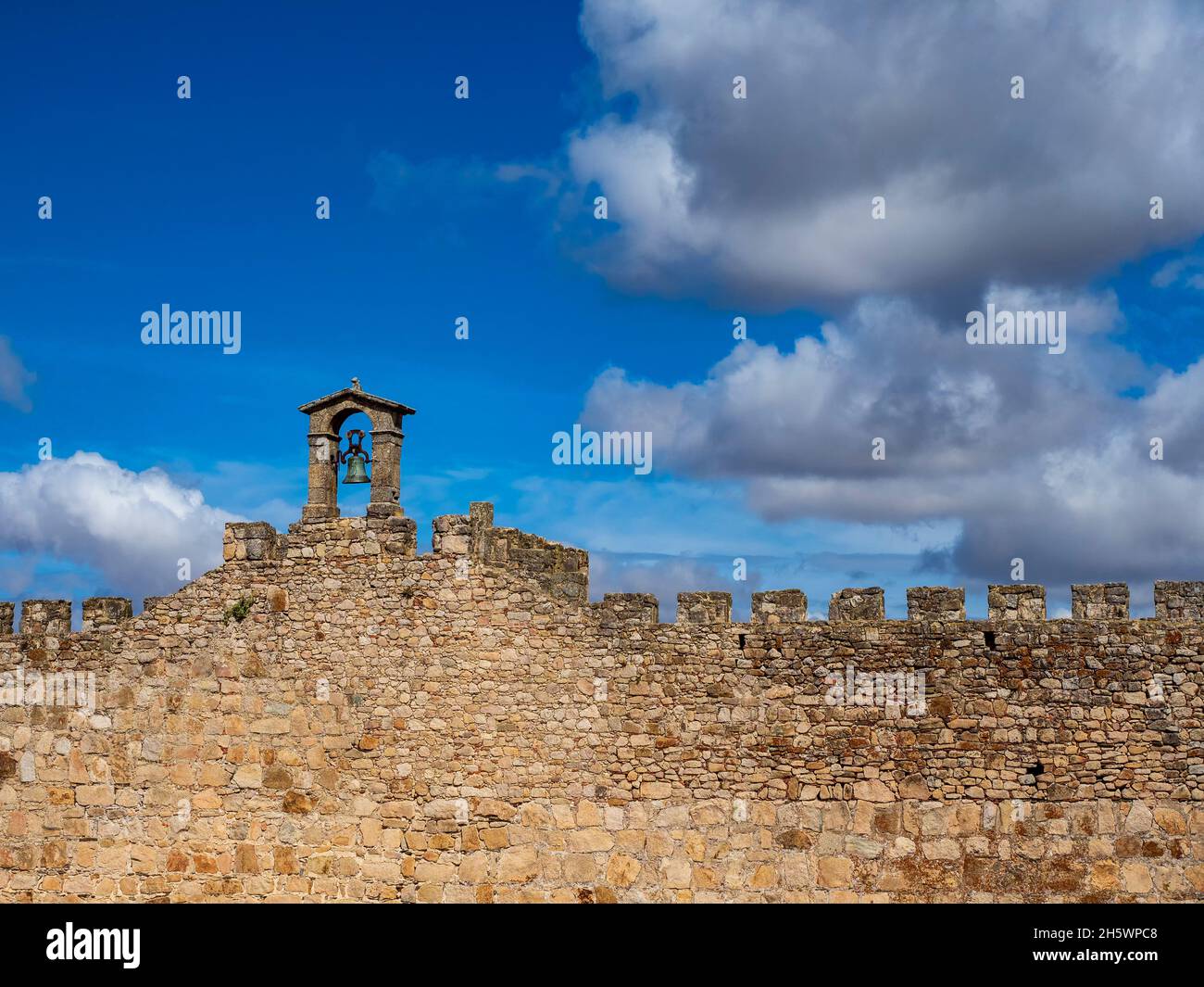Stone arch with a large bell on the wall of the castle of Trujillo de Cáceres. Stock Photo