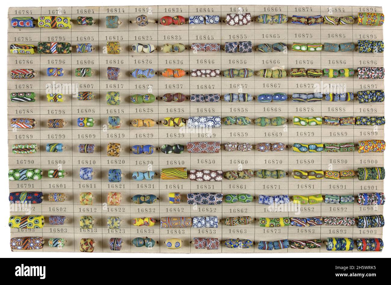 Card with a display of 120 handmade glass beads. Glass is wound around a piece of copper wire using pliers, after which the copper wire is pulled out. This creates the hole in the bead. The pattern in the bead is created by inlaid and melted mosaics. A labour-intensive process. Stock Photo