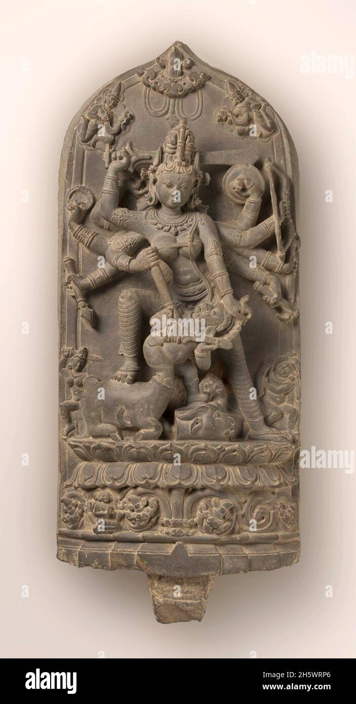 Stone carving of the Hindu goddess Durga Killing the Buffalo Demon. The demon was a shape-shifter. He first appeared as a buffalo and was beheaded by Durga; the buffalo's decapitated head can be seen lying on the ground. When the demon assumed human form, the goddess killed him again, this time using a trident. According to Hindu mythology, the goddess Durga was the only one capable of stopping the demon. In her eight arms she bears the weapons and symbols of the deities whose combined power she represents. Stock Photo