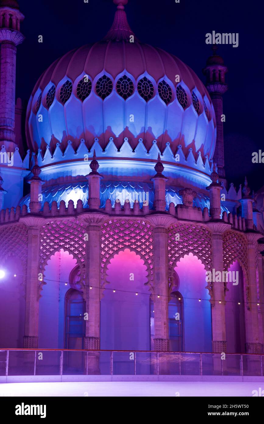 Pavilion Kaleidescope. The Royal Pavilion, Brighton, lit up with coloured LED uplighters behind the winter ice skating rink erected in the Pavilion gardens. Brighton, East Sussex, England, UK Stock Photo
