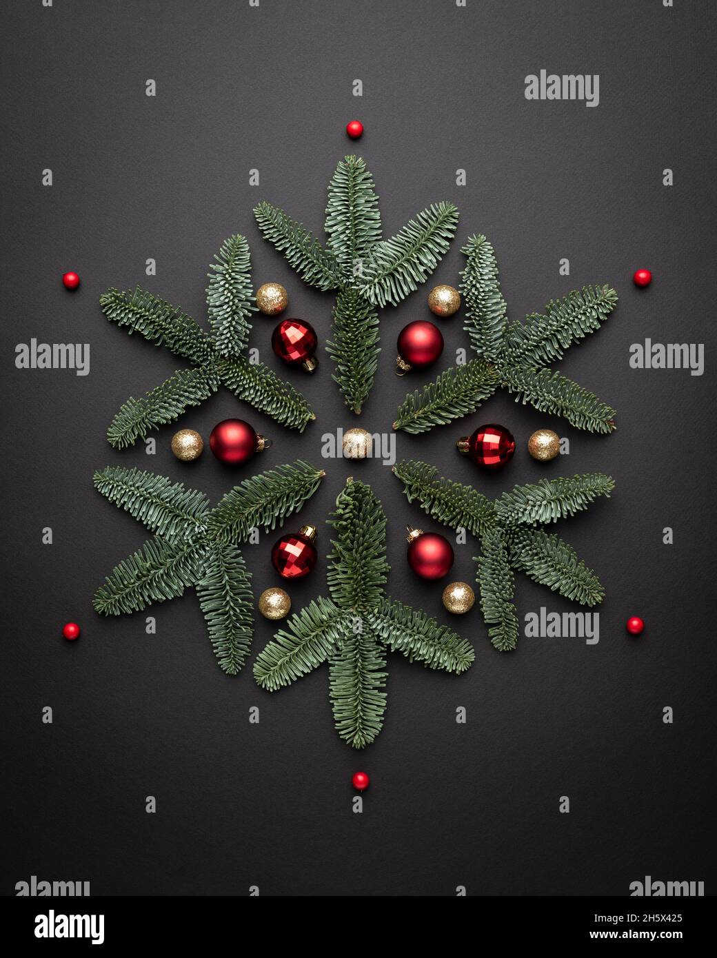 Christmas card with a decorative snowflake made of Christmas decorations and fir branches on a black background Stock Photo