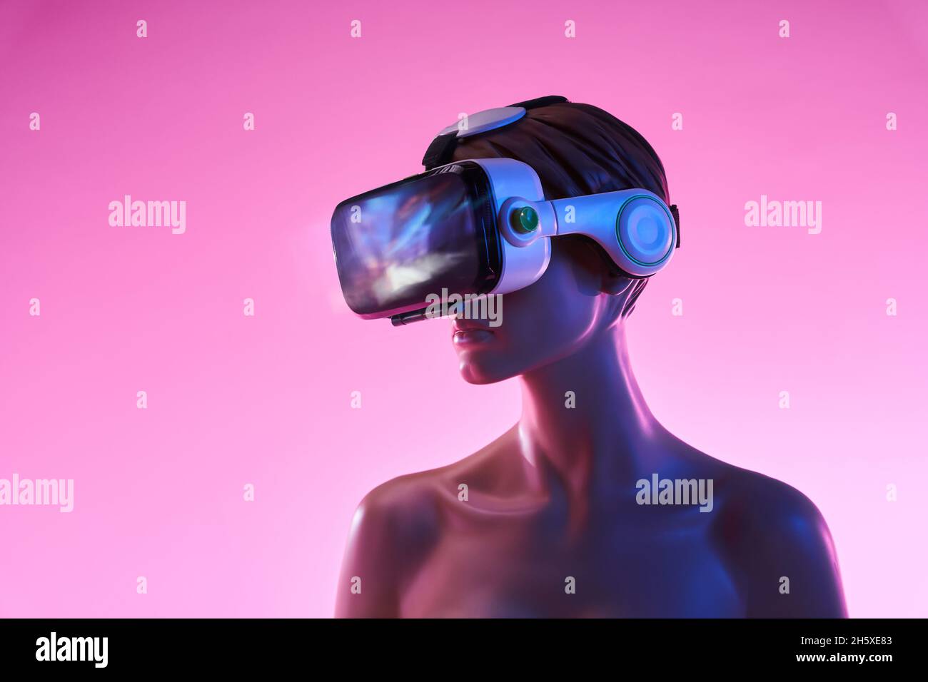 Female dummy with VR goggles placed against bright pink background as ...