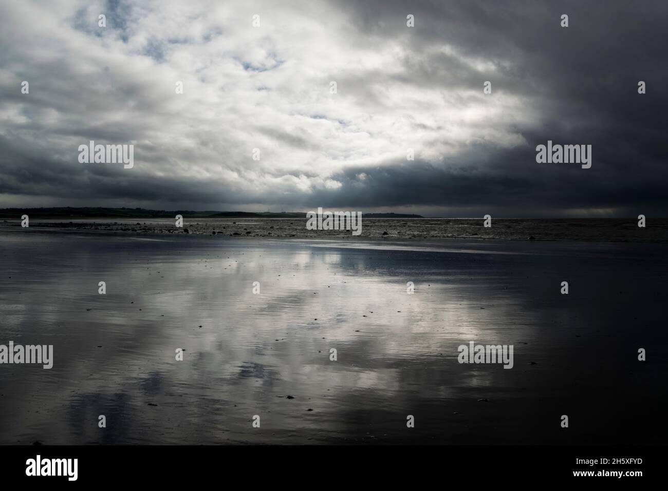 Refection of stormy clouds in the receding tidal water Stock Photo