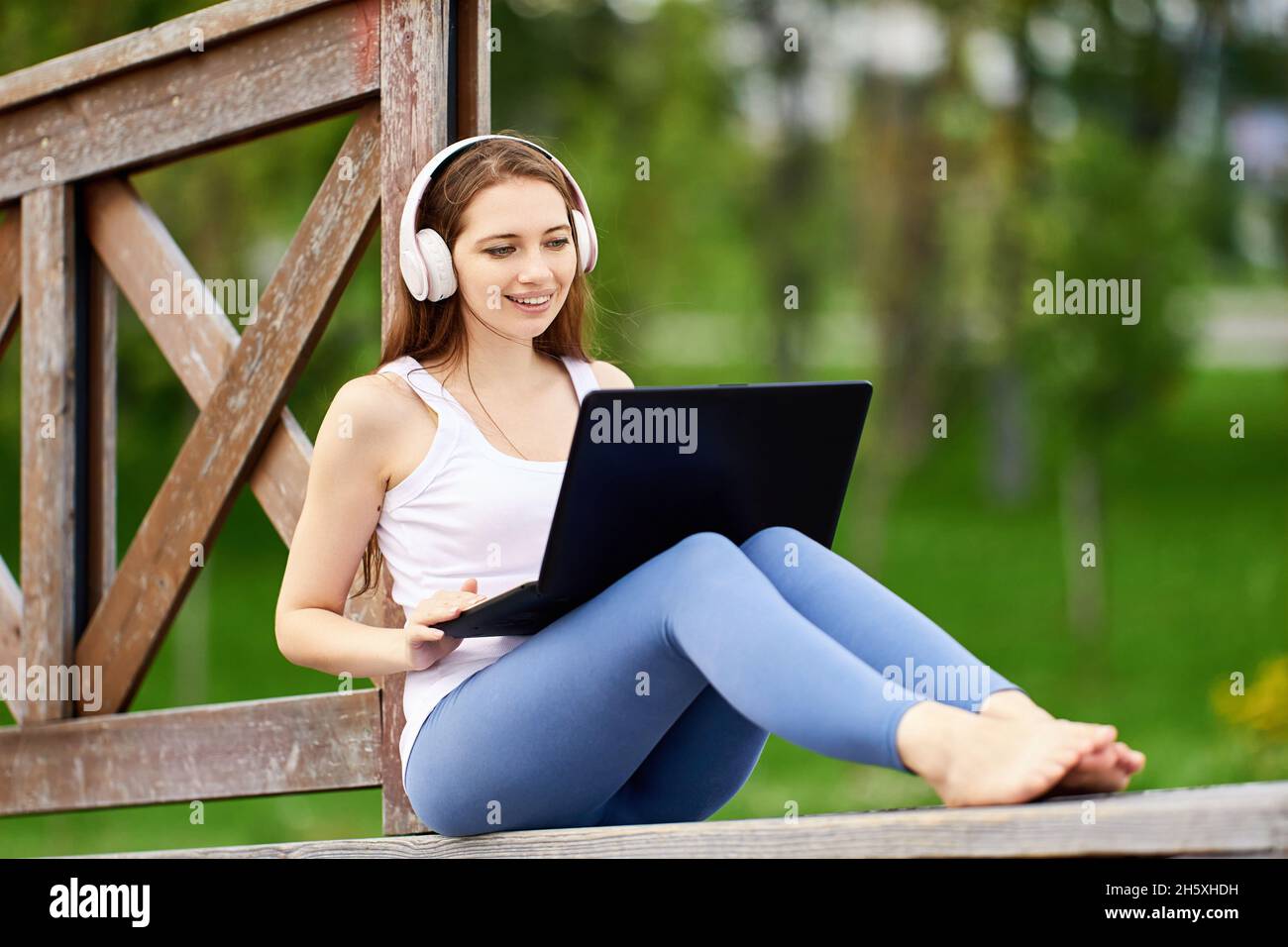 Online learning or teleworking using laptop connected internet via 5g network, young woman does e-learning while visiting public park. Stock Photo