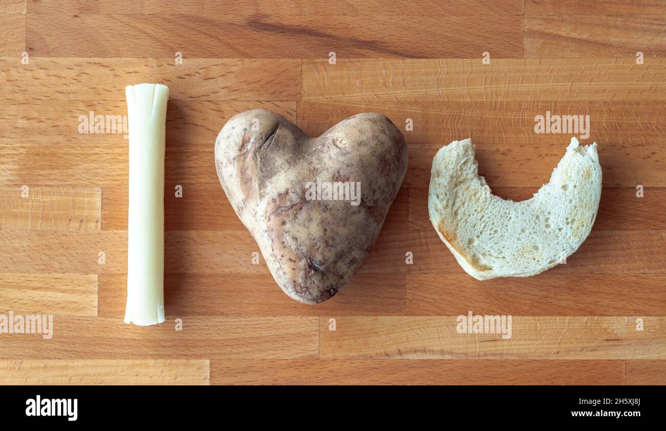 I love you message spelled out using food items including a mozzarella string cheese stick, heart shaped potato and an English muffin half with a bite Stock Photo