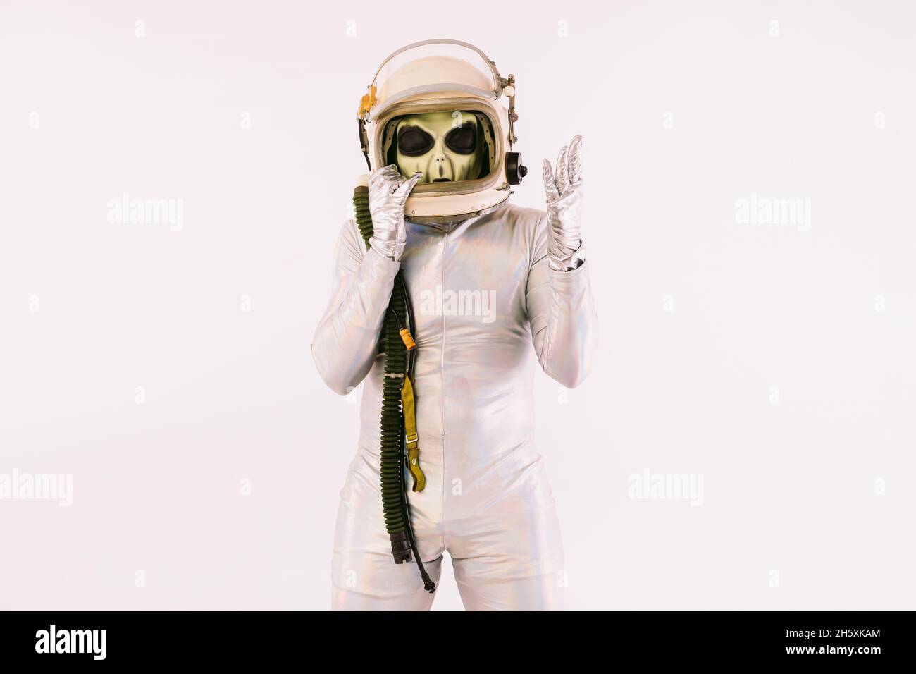Person dressed in silver suit and green alien mask, wearing a cosmonaut ...