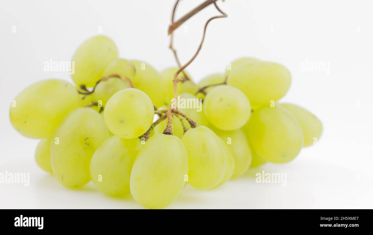 Fresh bunch of juicy grapes rotate on a white background. Ripe juicy grapes rotate on a plate. Close-up of a bunch of white grapes. Stock Photo
