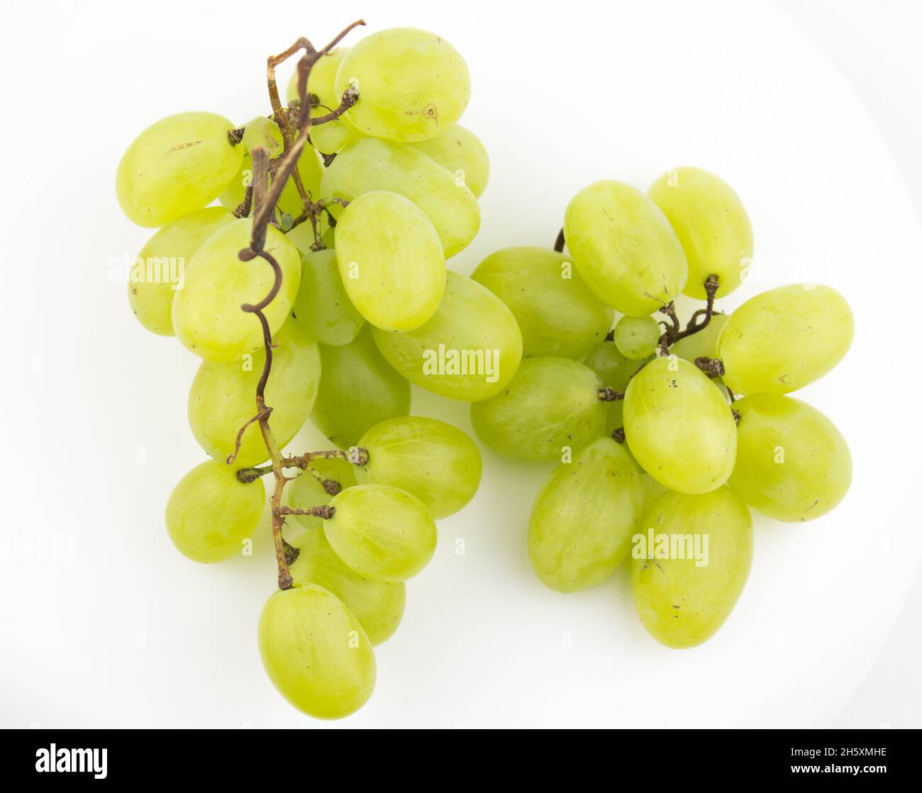 Fresh bunch of juicy grapes rotate on a white background. Ripe juicy grapes rotate on a plate. Close-up of a bunch of white grapes. Stock Photo