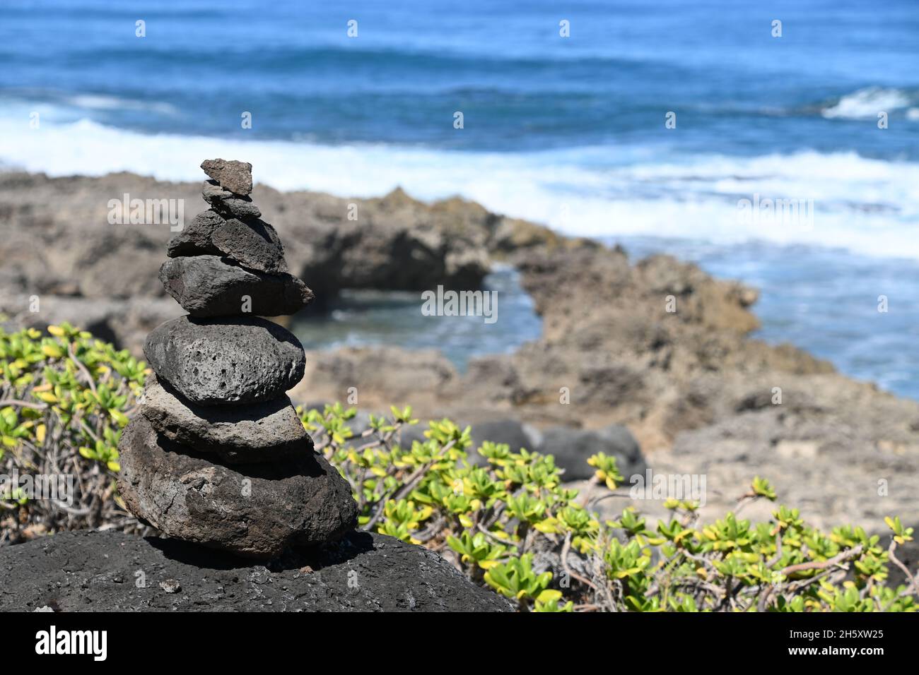 Heap of stacked rocks; beach and ocean surf, Kaena Point in Oahu ...