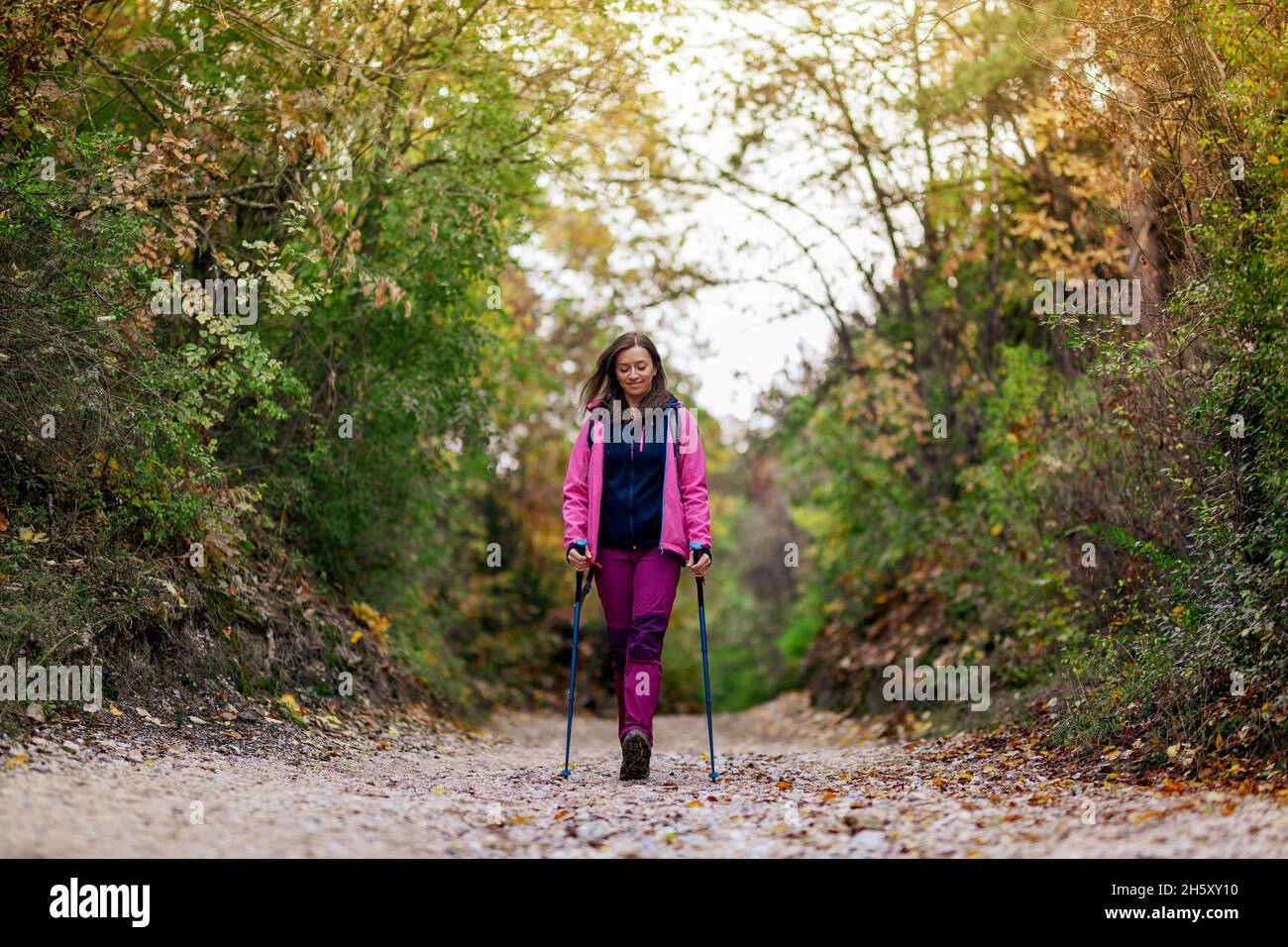 Hiker girl walking towards camera on a wide trail in the mountains ...