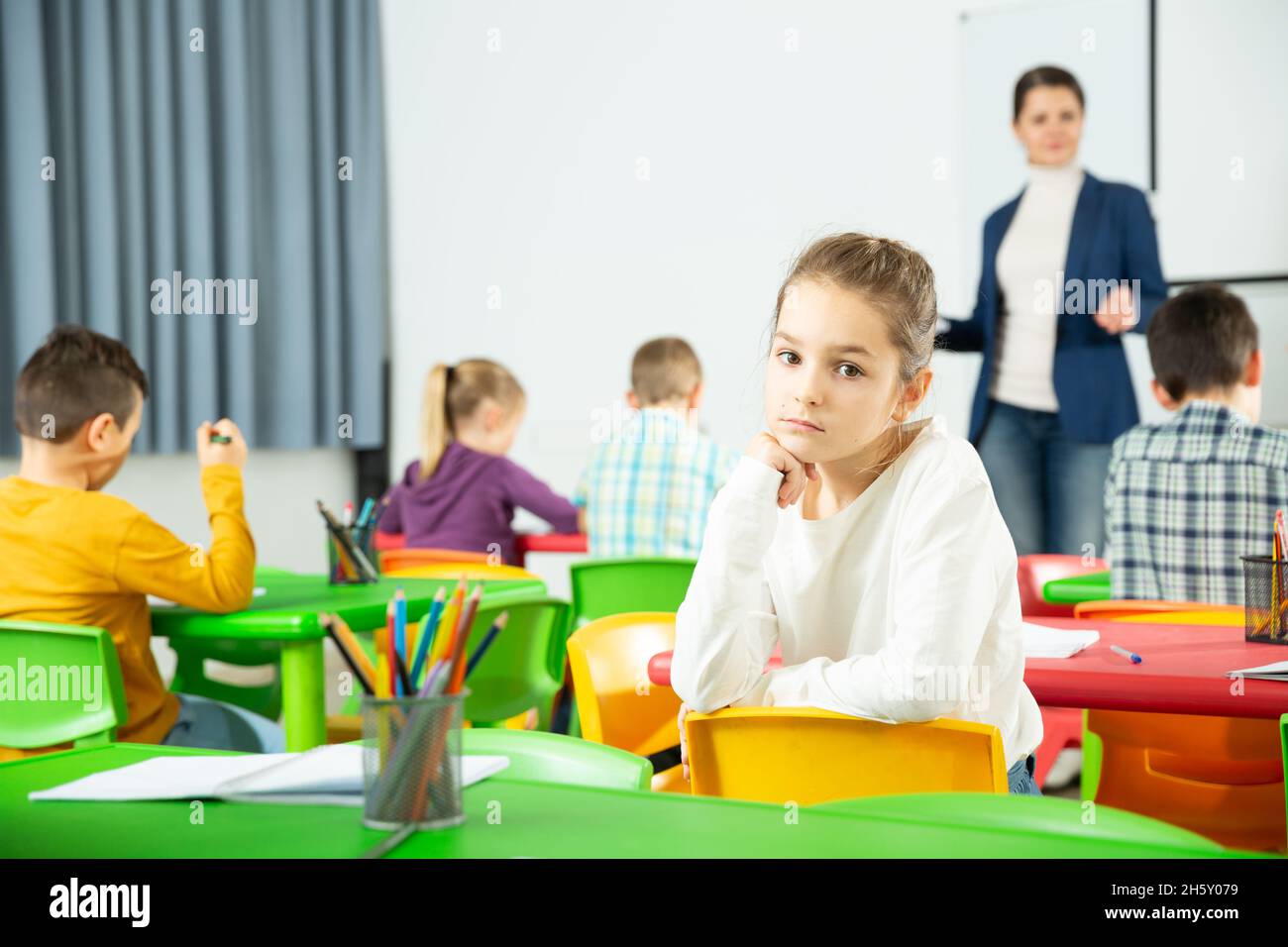 Portrait of tired schoolgirl sitting in classroom elementary school Stock Photo