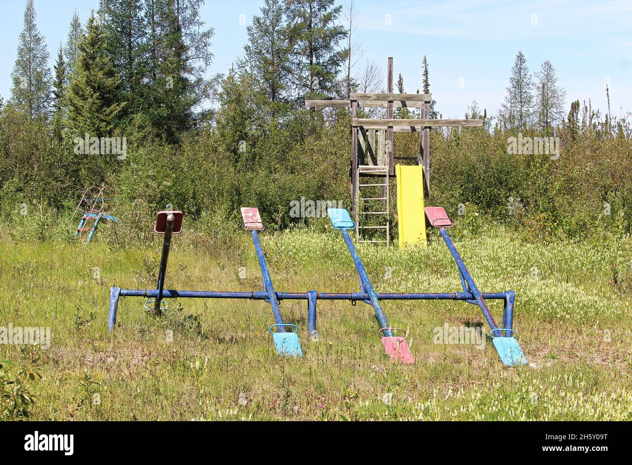 An unmaintained playground with overgrown grass Stock Photo