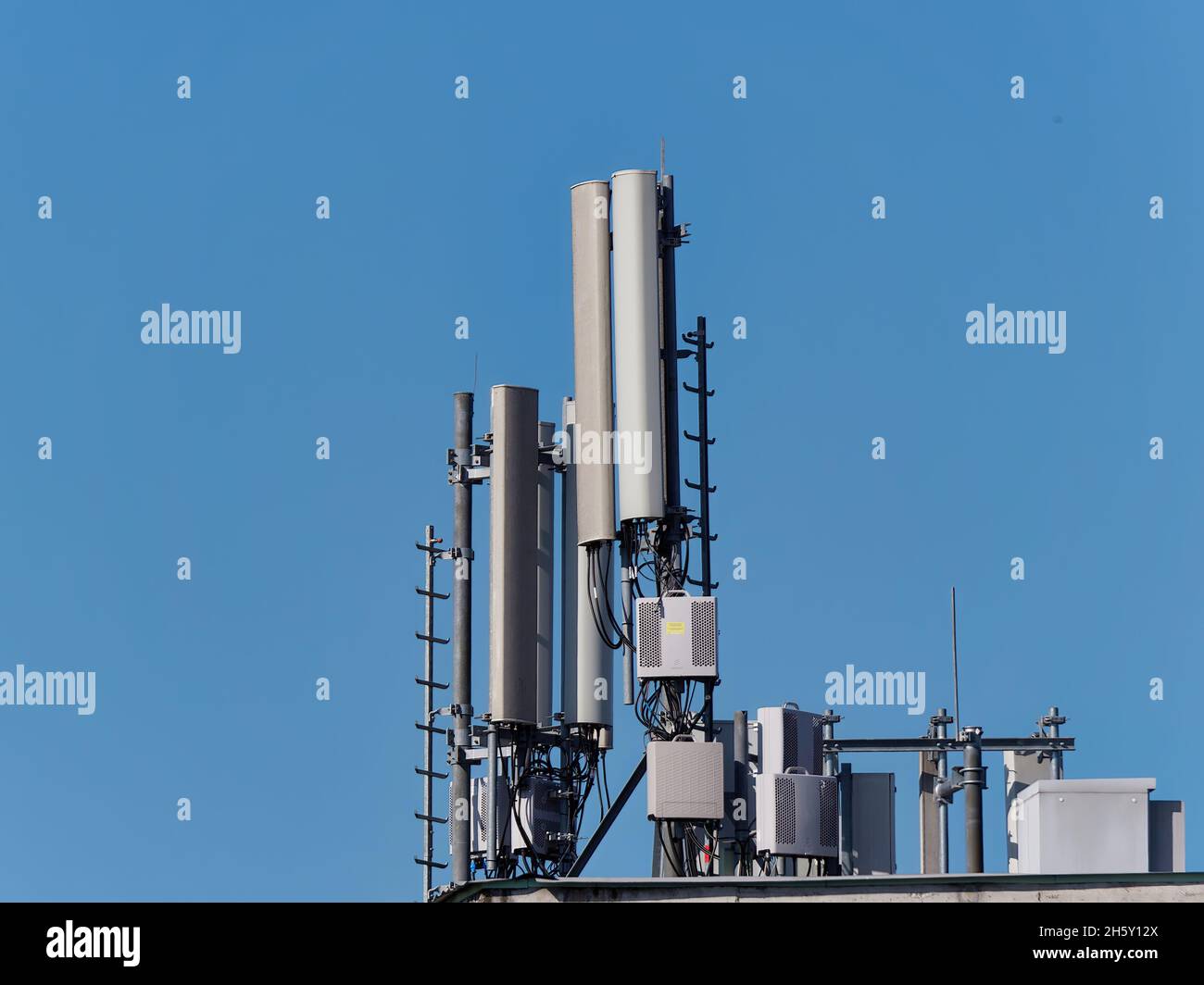 Mobile phone base station atop of a building against a blue sky on a