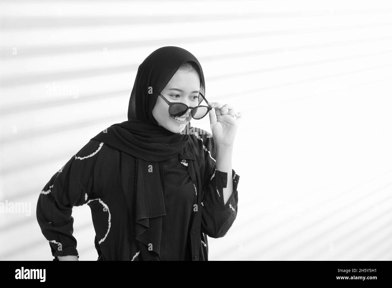 Indonesian female teenage Muslim wearing black eye glasses in black and white portrait Stock Photo