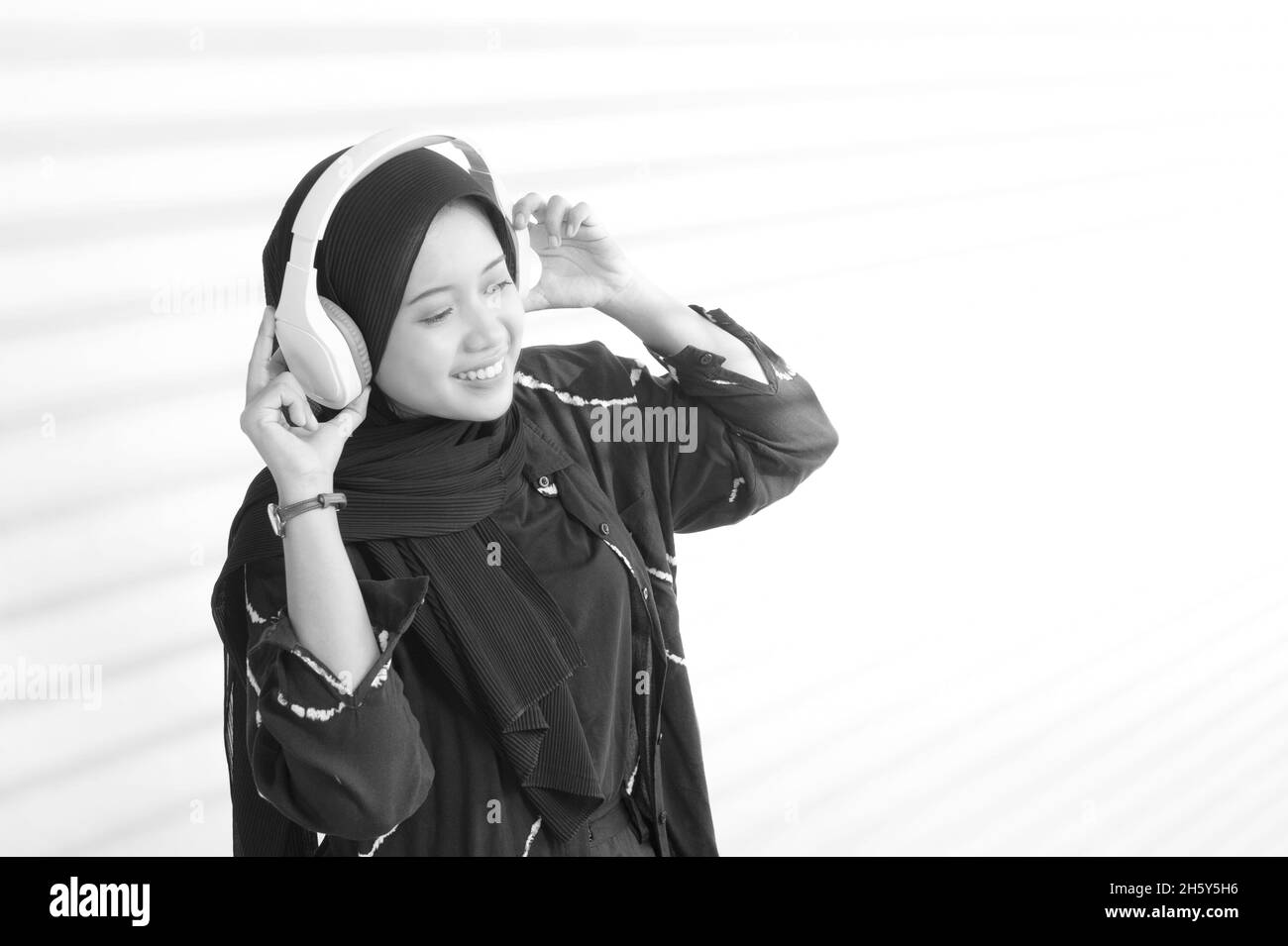 Indonesian female teenage Muslim  holding headset in black and white portrait Stock Photo
