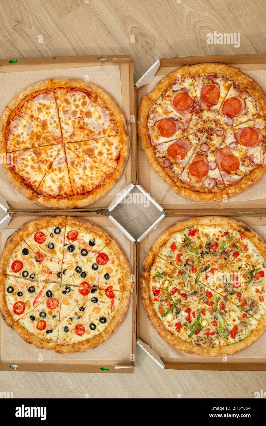 Four different cut pizzas are in square boxes. Meat and vegetarian