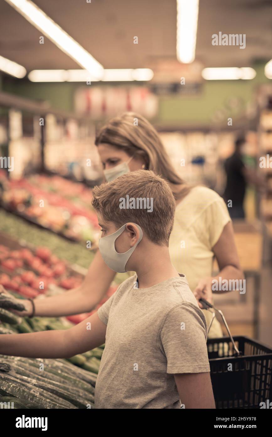 Chicago,IL- August 21, 2021:Mother and  child wearing masks shopping at supermarket for editorial use only Family wearing masks picking fruits at supe Stock Photo