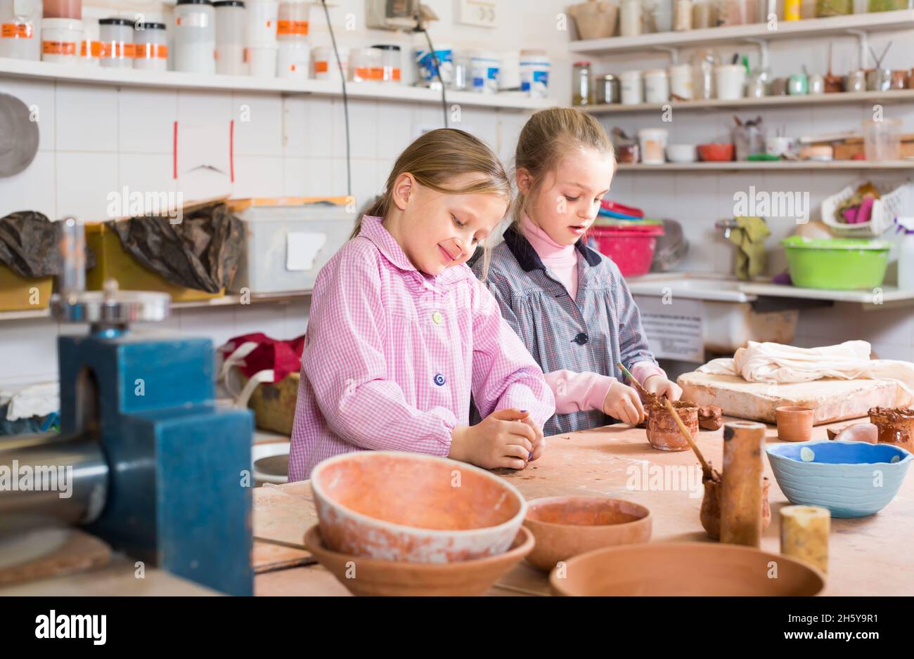 Smiling schoolgirls training to make ceramics during arts Stock Photo
