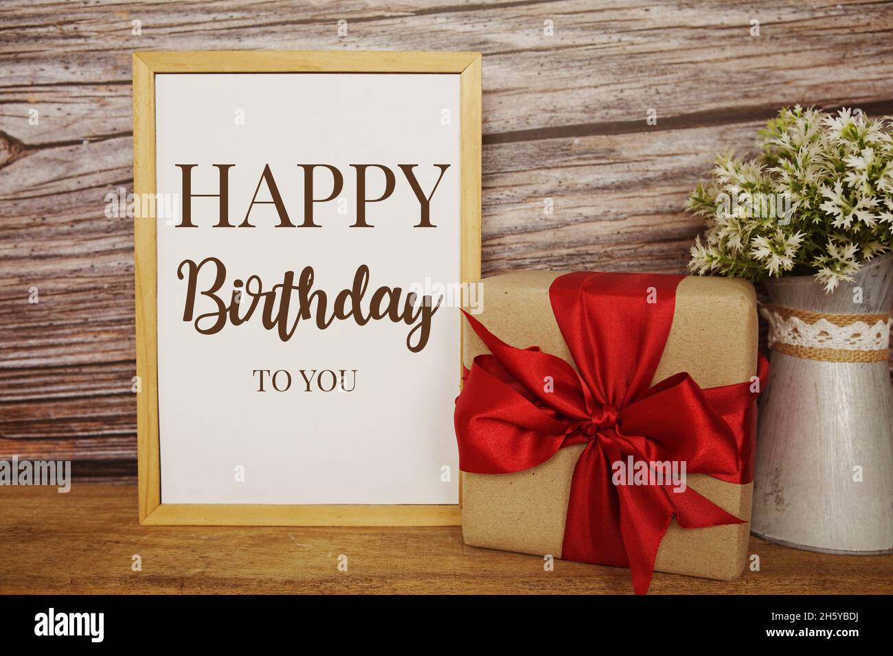 Blackboard with the text HAPPY BIRTHDAY TO YOU with gift box and red ribbon  on wooden background Stock Photo - Alamy