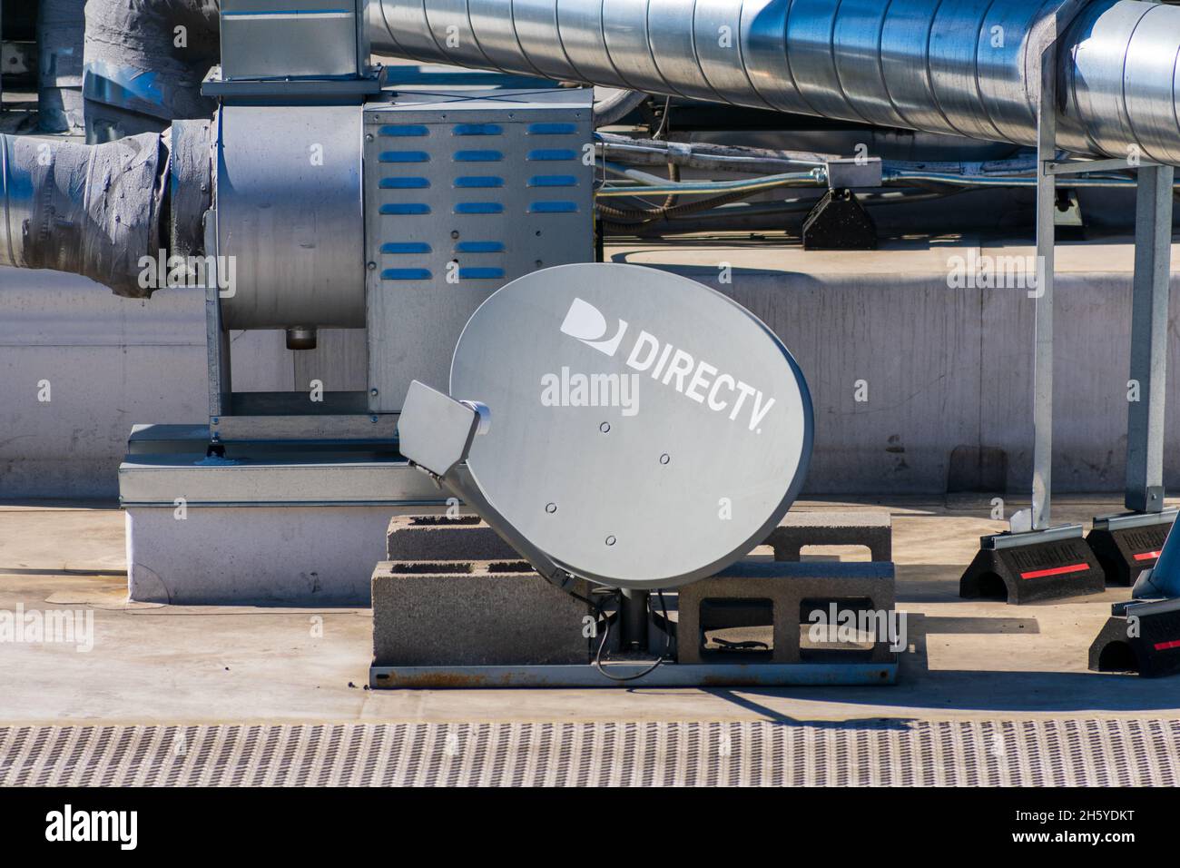 DirecTV satellite dish antenna with a multi-satellite LNB installed on the building roof. DirecTV is an American direct broadcast satellite service pr Stock Photo