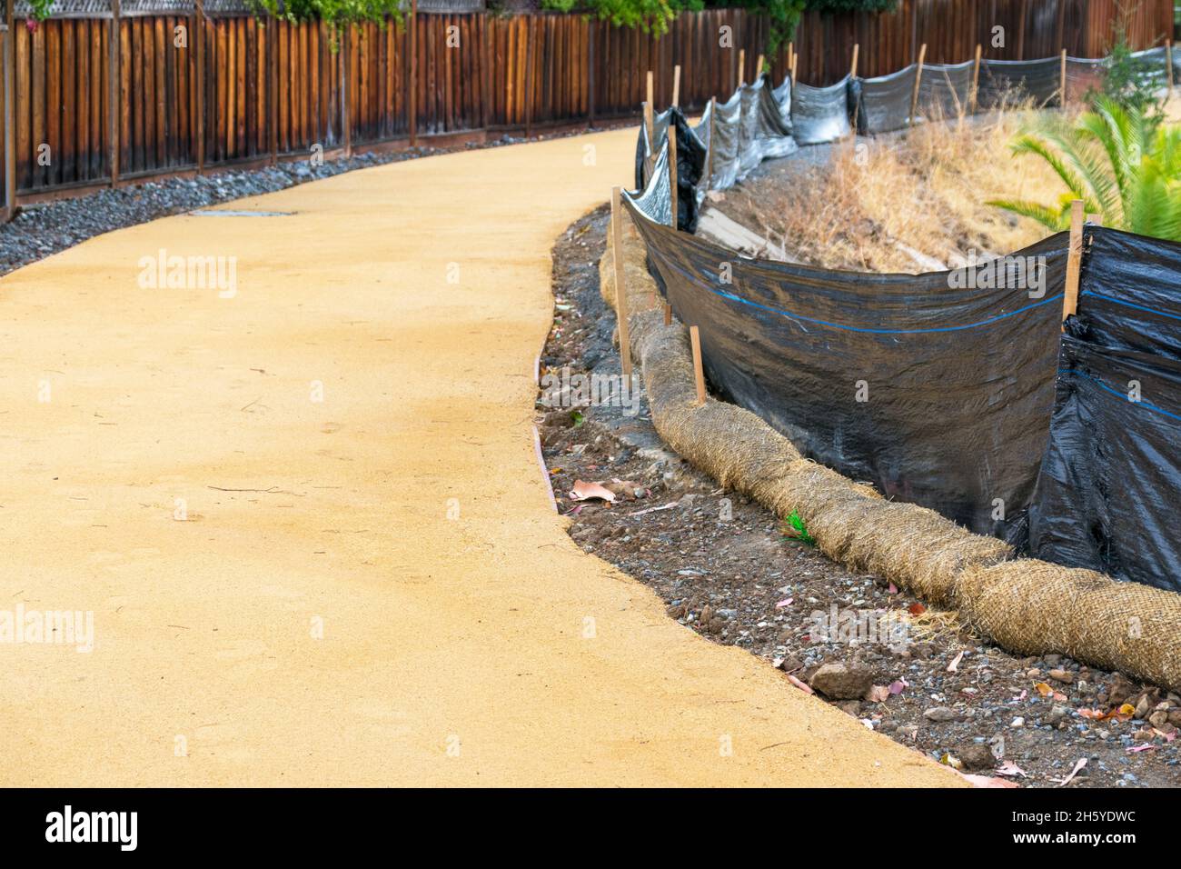 Straw wattle and plastic fence are placed along the waterway to reduce soil erosion, debris runoff and retain sediment during pedestrian trail constru Stock Photo