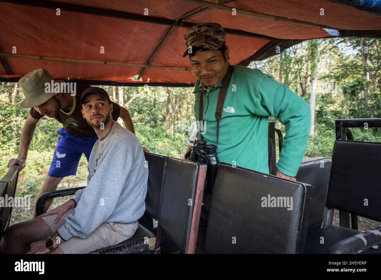 November 2017. Nature guide, Rajendra Chaudhary (right), became a guide six years ago after graduating with a humanities degree from university. He love being out in and learning about nature. Jeep safaris are replacing elephant safaris in Chitwan National Park and some of the community forests, catering to tourists more sensitive to animal rights issues or who are simply looking for a diferent experience. Kumrose Community Forest, Kumrose, Nepal. Stock Photo