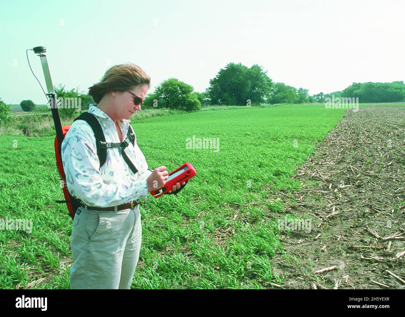 A hydrologist uses a Global Positioning System (GPS) and personal digital assistant (PDA) to record status of a Conservation Reserve Program (CRP) filter strip planting in Cass County, Iowa ca. 2011 or earlier Stock Photo