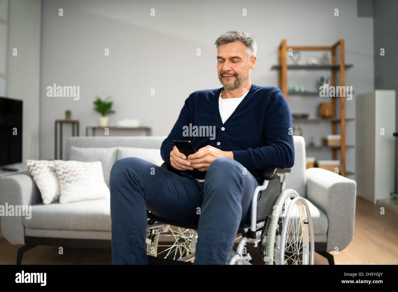 Older Man With Disability Using Smartphone Or Mobile Phone Stock Photo