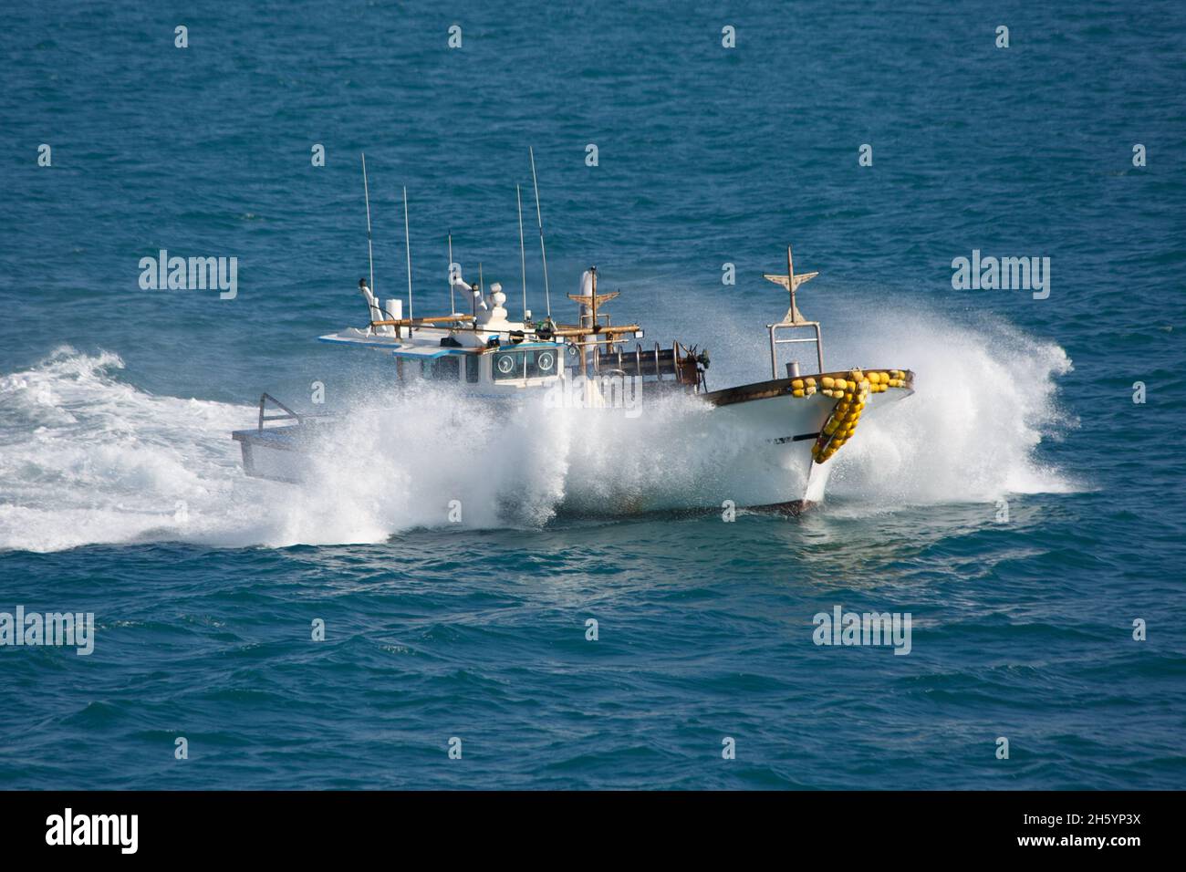 The fishing boat in sea splashes, floats with high speed. Stock Photo