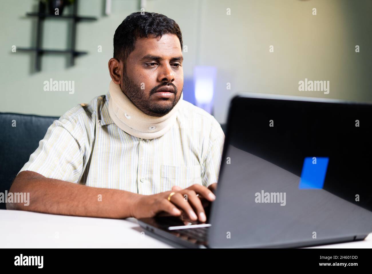fat man with neck brace working on laptop due to neck pain during work
