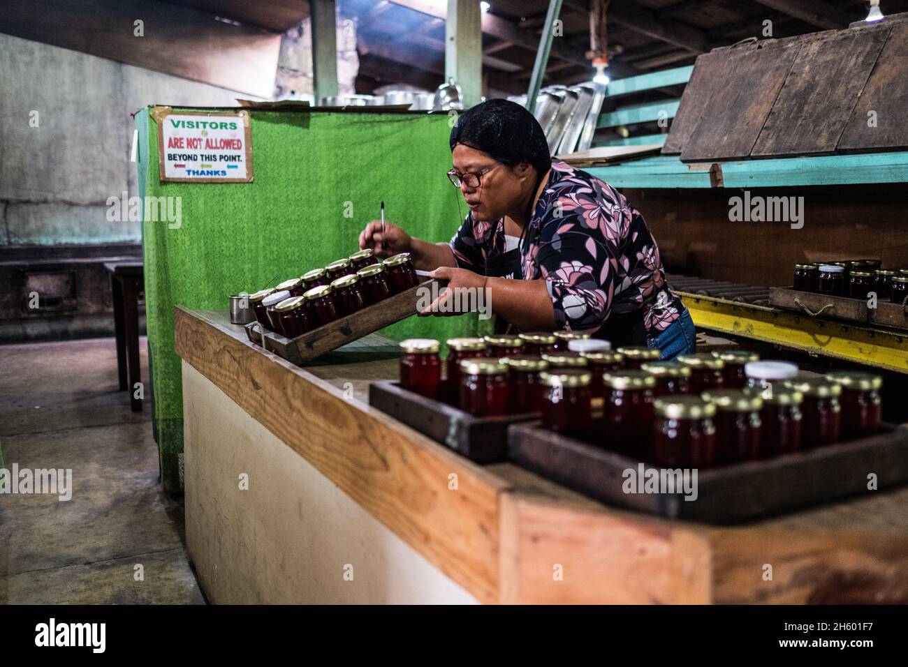 July 2017. Head cook, Elizabeth Palcay, does final quality control checks and finishes packaging hibiscus jelly. The Kalihan Educational Foundation (KEF) runs a small jam, jelly, and other prepared foods making operation as part of their enterprise development programs. Imugan, Nueva Vizcaya, Philippines. Stock Photo