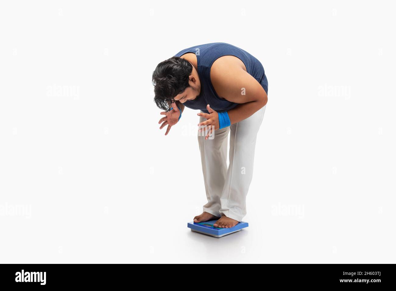 Portrait of a fat man standing on weighing machine and measuring weight with frustration. Stock Photo