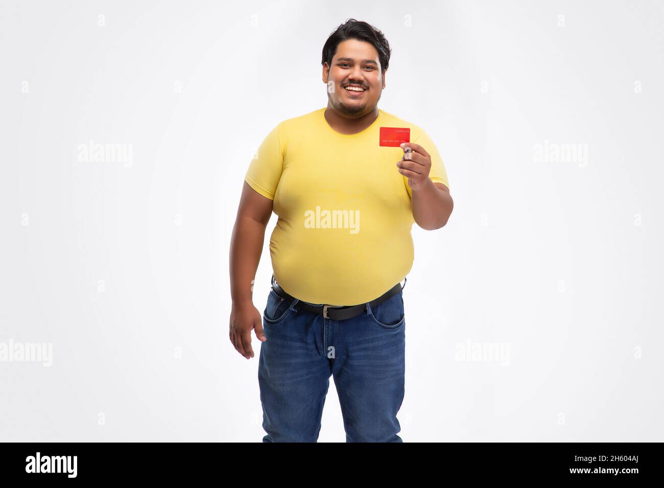 Portrait of a fat man smiling and showing credit card against plain background. Stock Photo
