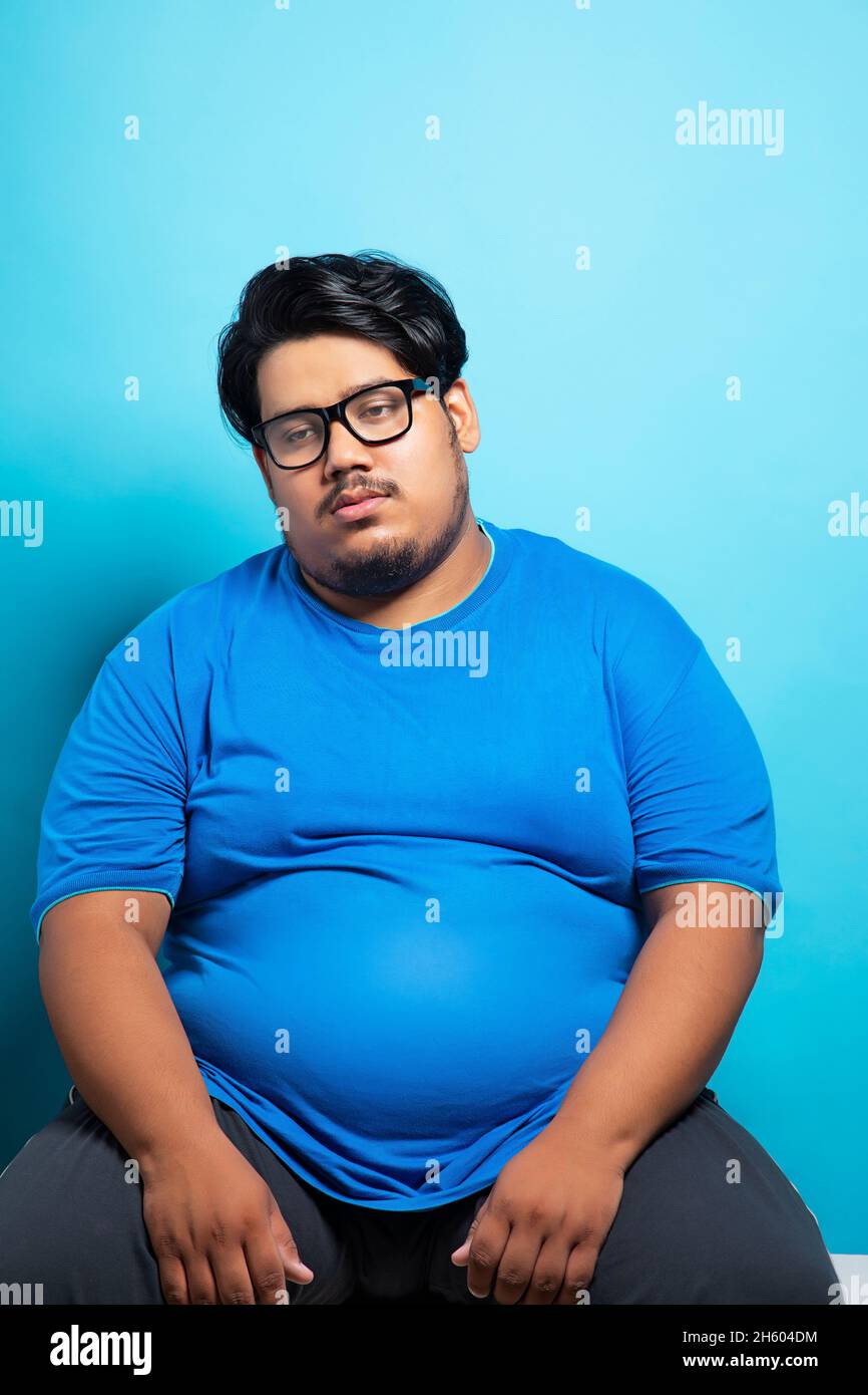 Porrait of a fat man wearing eyeglasses sitting with a dull tired  expression on face Stock Photo - Alamy