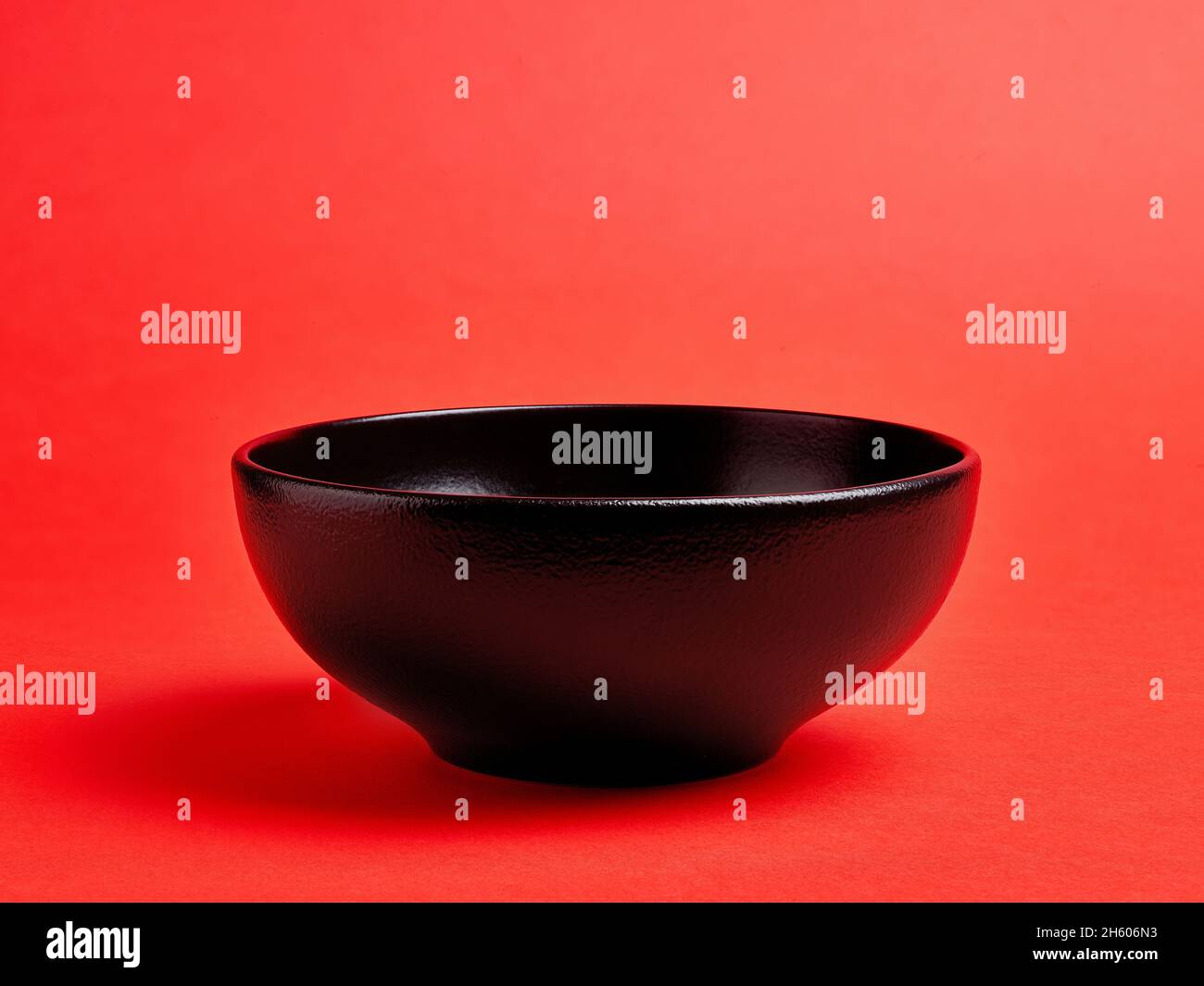 Empty black ceramic bowl on red background Stock Photo