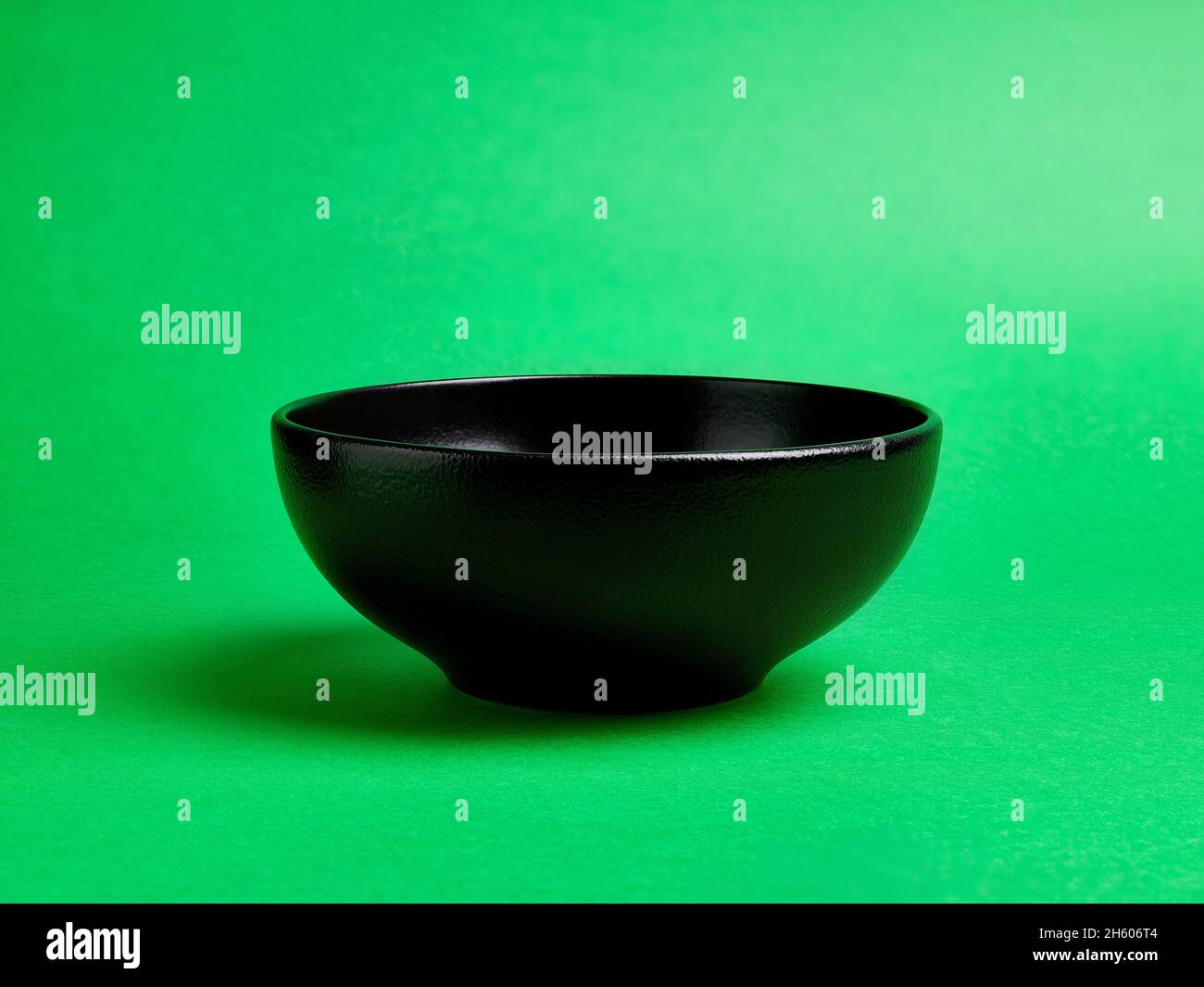 Empty black ceramic bowl on green background Stock Photo