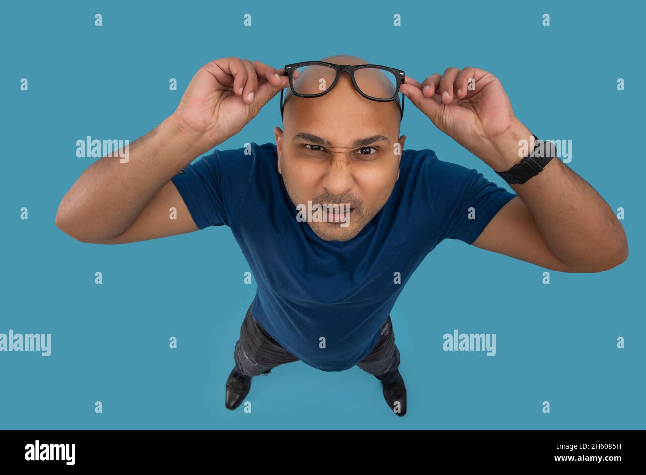 Portrait of a  bald man with confused expression lifting his eyeglasses up to his shaved head. Stock Photo