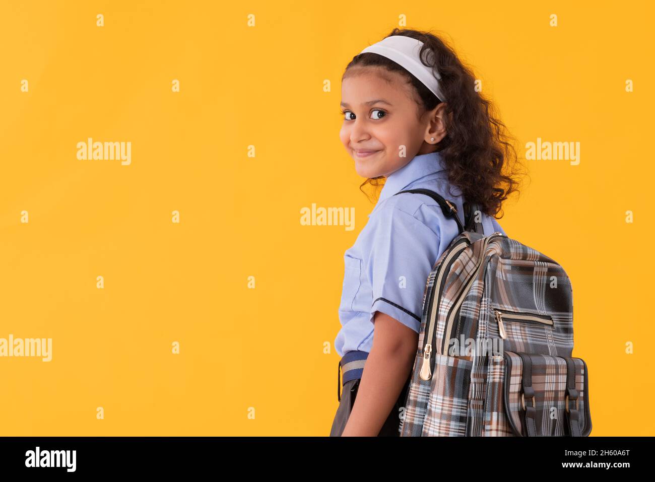 A HAPPY GIRL IN UNIFORM TURNING BEHIND AND LOOKING AT CAMERA Stock Photo