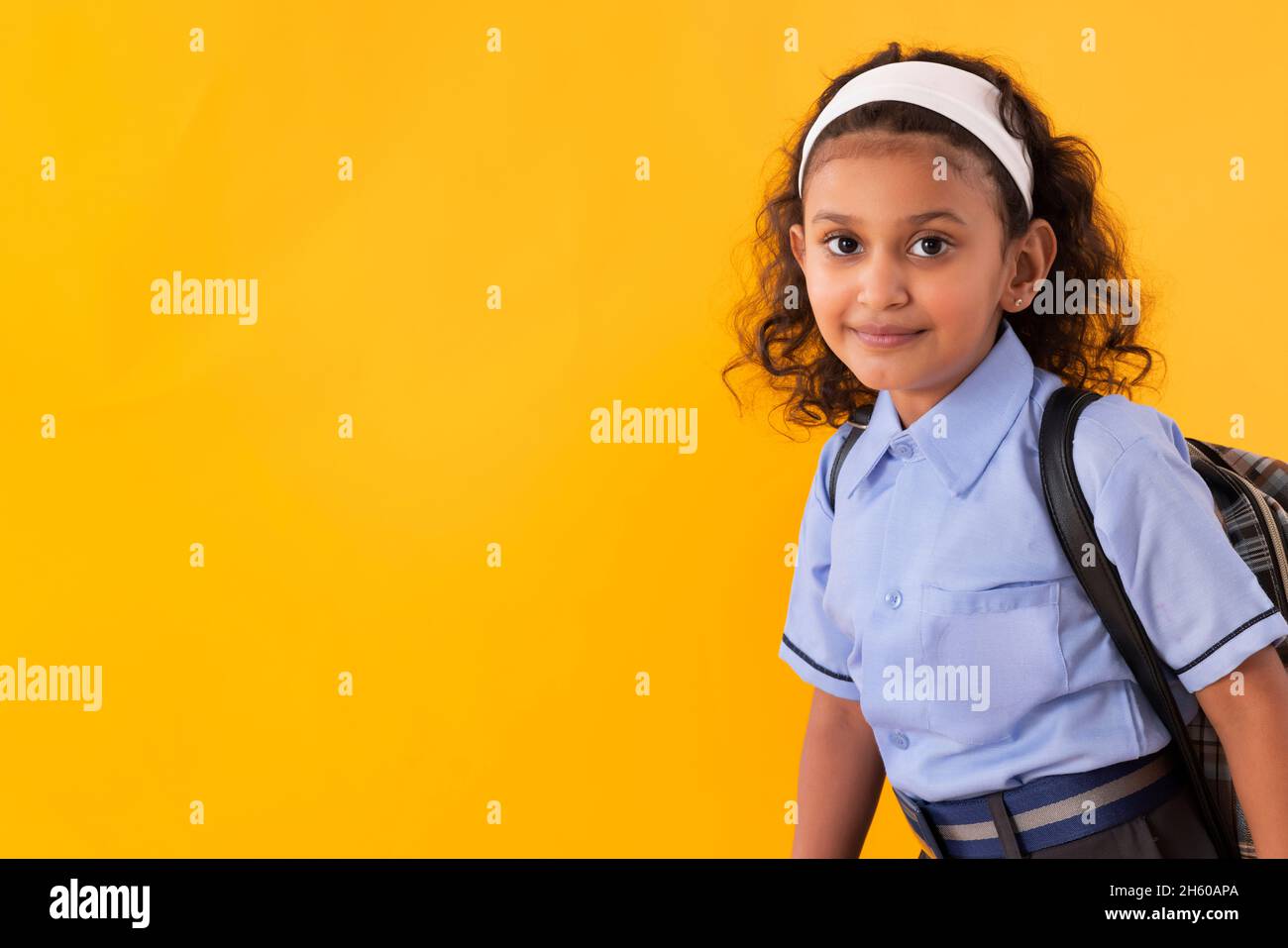 A YOUNG GIRL IN UNIFORM STANDING AND LOOKING AT CAMERA Stock Photo